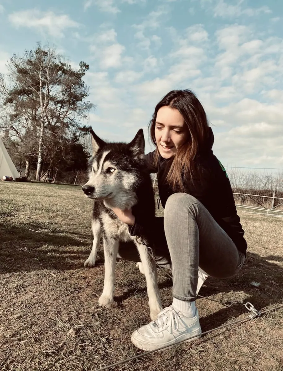 Julianne accroupie auprès d’un husky, en extérieur